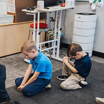 Two elementary boys praying in the classroom