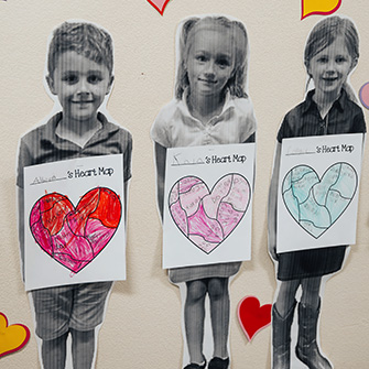 Three student photos with hearts on classroom wall